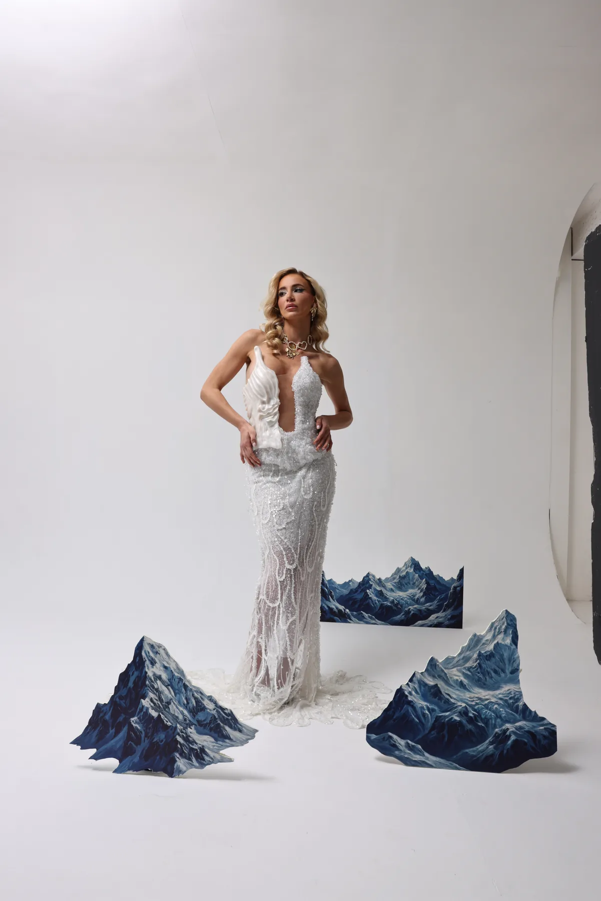 White embellished dress staged between painted mountain forms